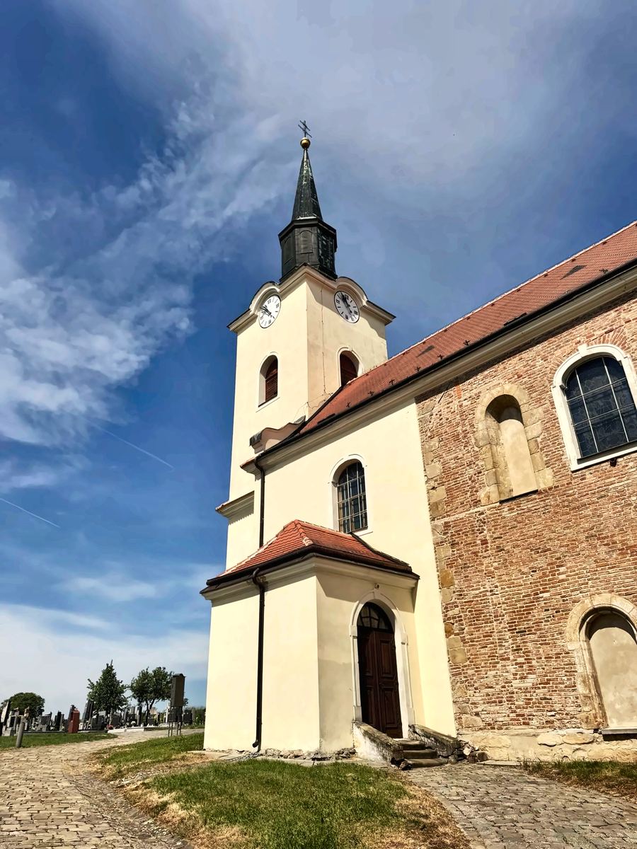 Žlutý kostel s věží proti modrému nebi