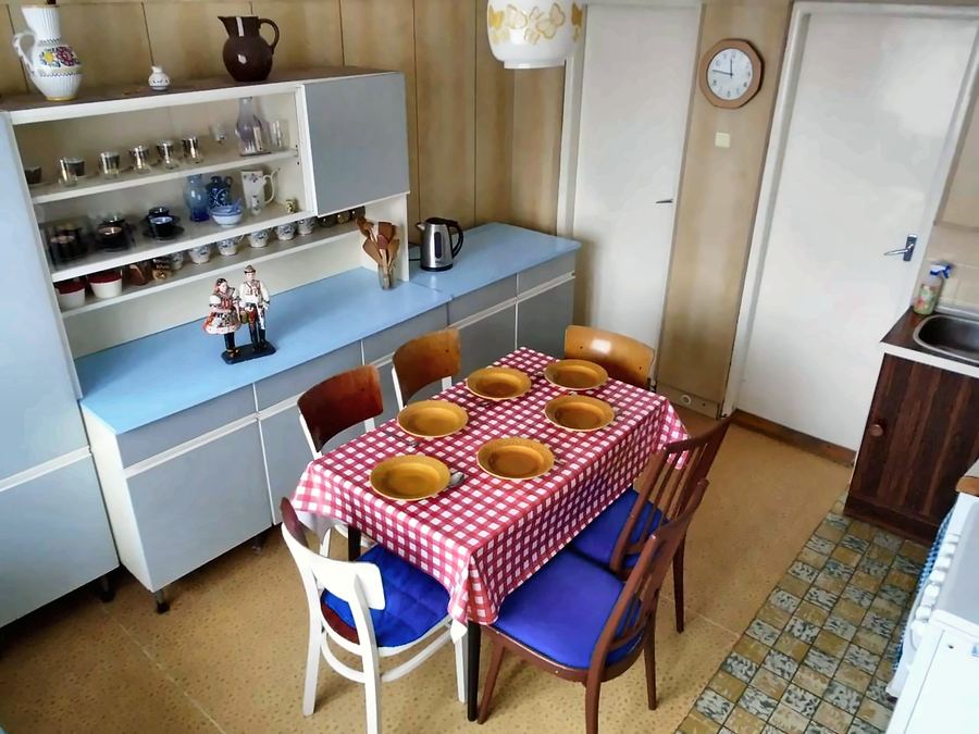 Retro kuchyň s kostkovaným ubrusem, kredencí a modrými polštářky na židlích