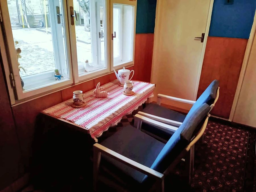 Stolek u okna s kostkovaným ubrusem a dvě křesla